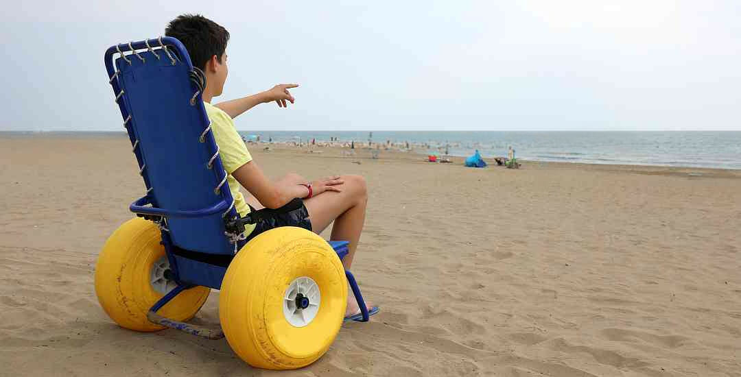 young boy sitting in a beach wheelchair that has inflatable tires