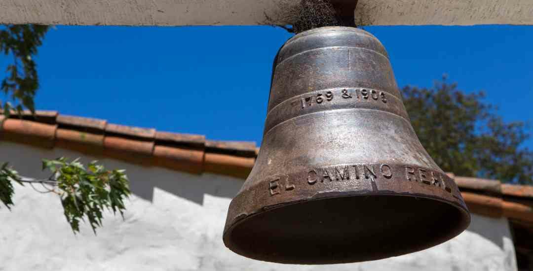 A bell hangs on the side of a building.